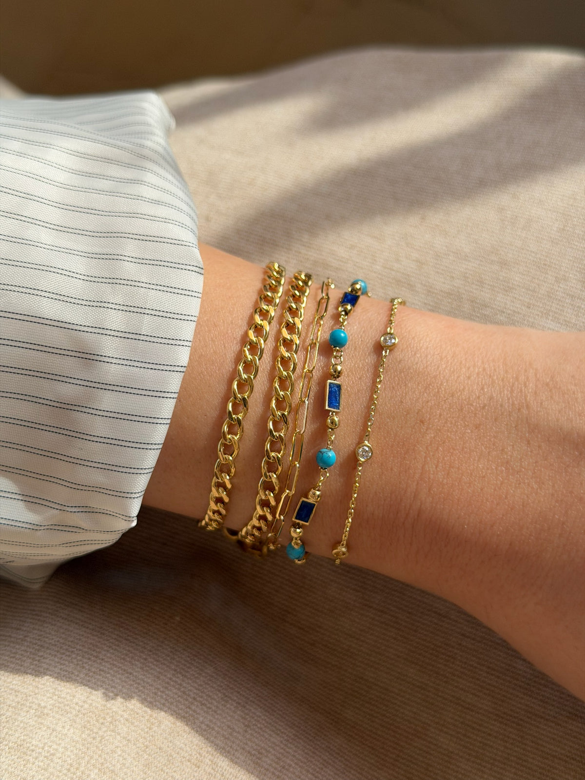 Stack of 18K gold bracelets including this dainty paperclip bracelet, with other styles