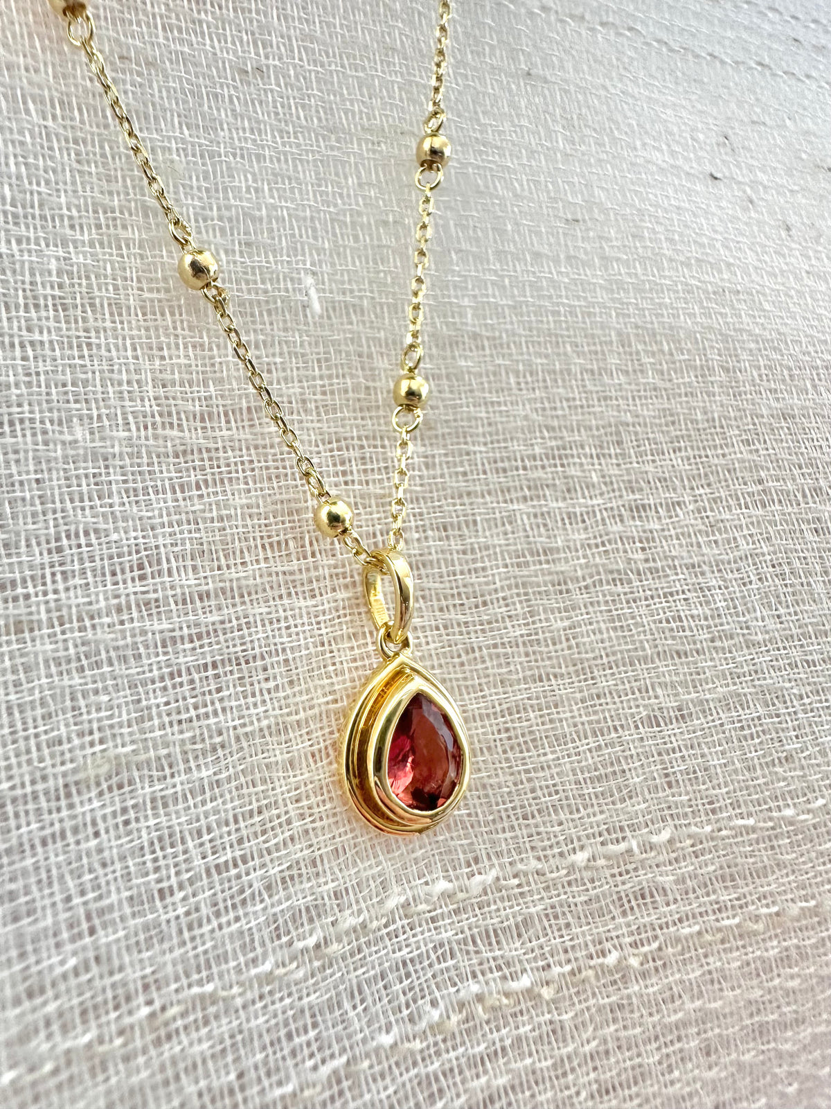 Pink tourmaline pendant with a solid gold back and an opening behind the stone