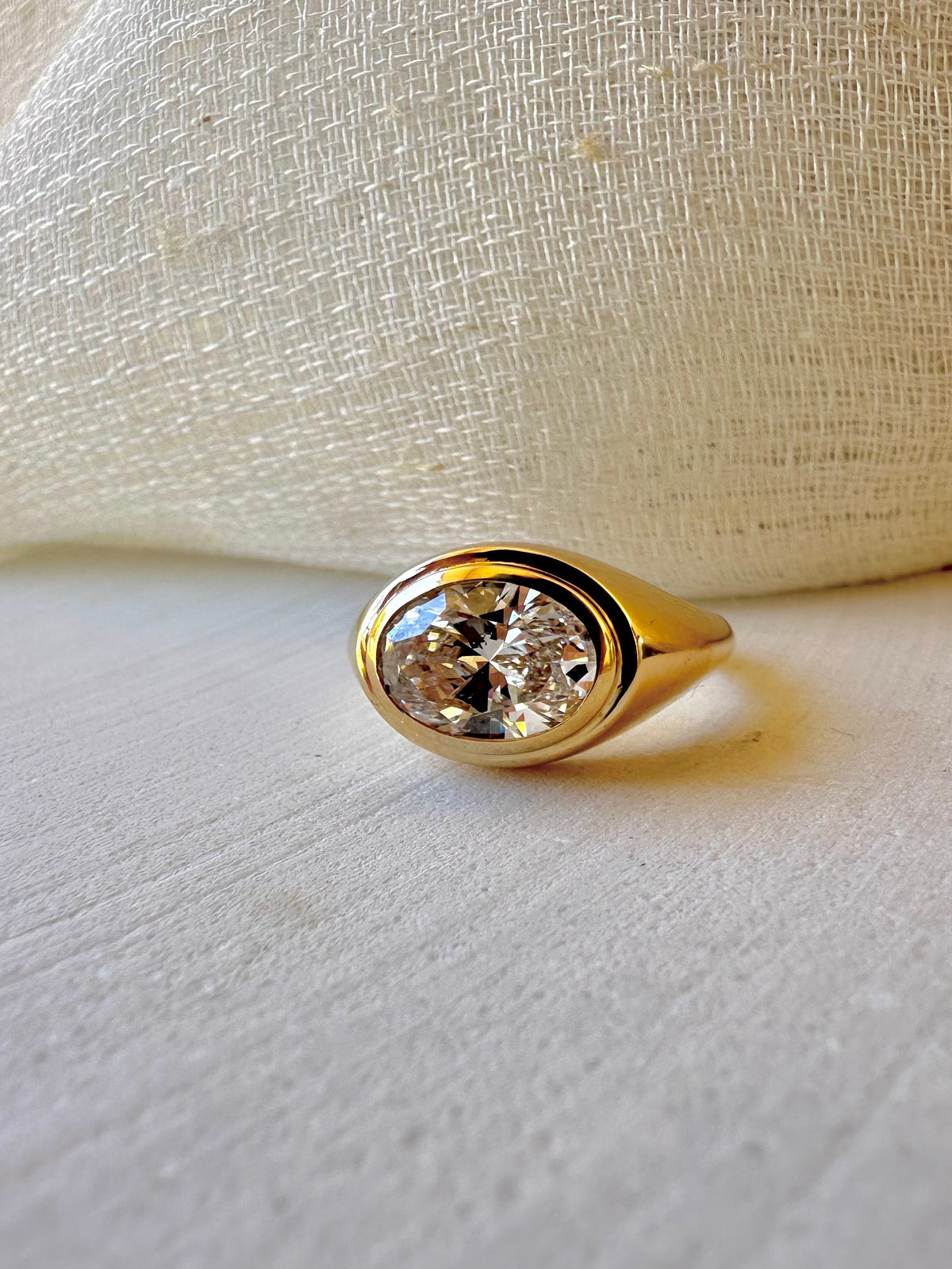 Polished dome signet ring with a 2 carat bezel set oval lab diamond