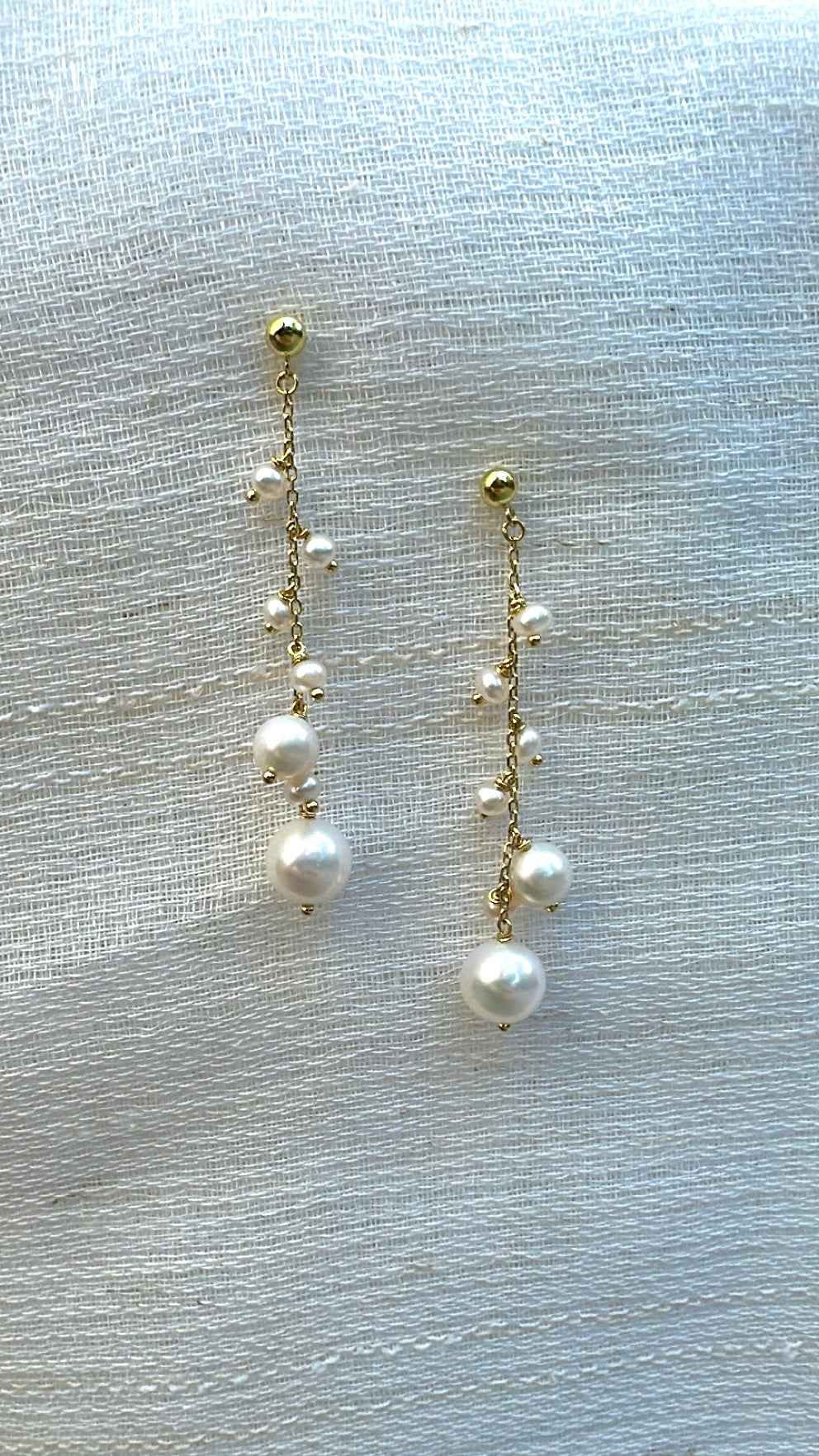 Pearls of different sizes hang from an 18K gold chain on each earring
