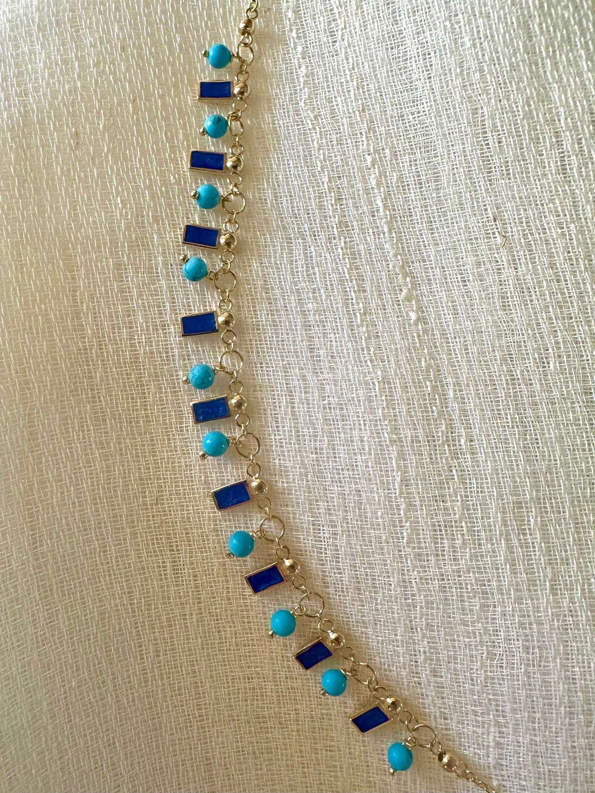 Turquoise and enamel necklace layered with gold jewelry