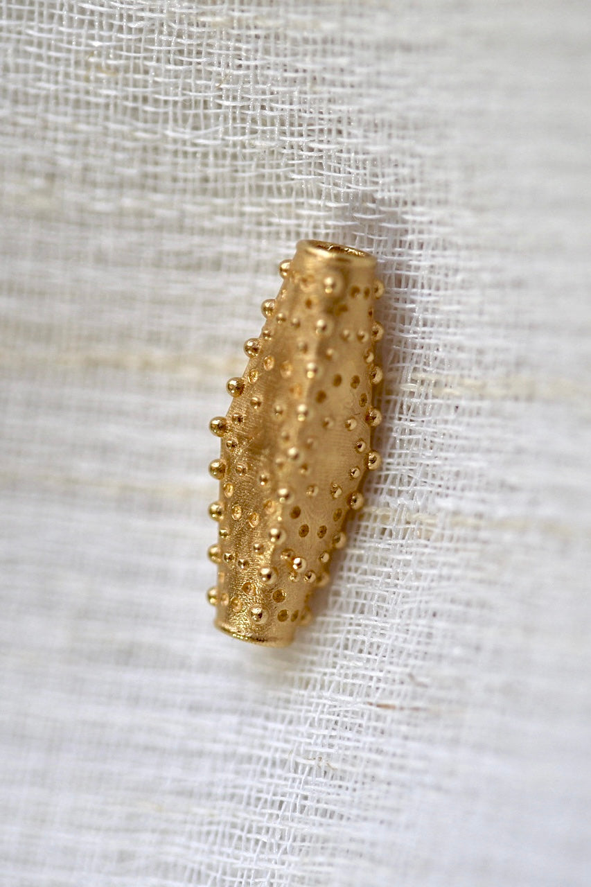 Gold slider with a bead and dent pattern on its surface, 20mm by 8mm