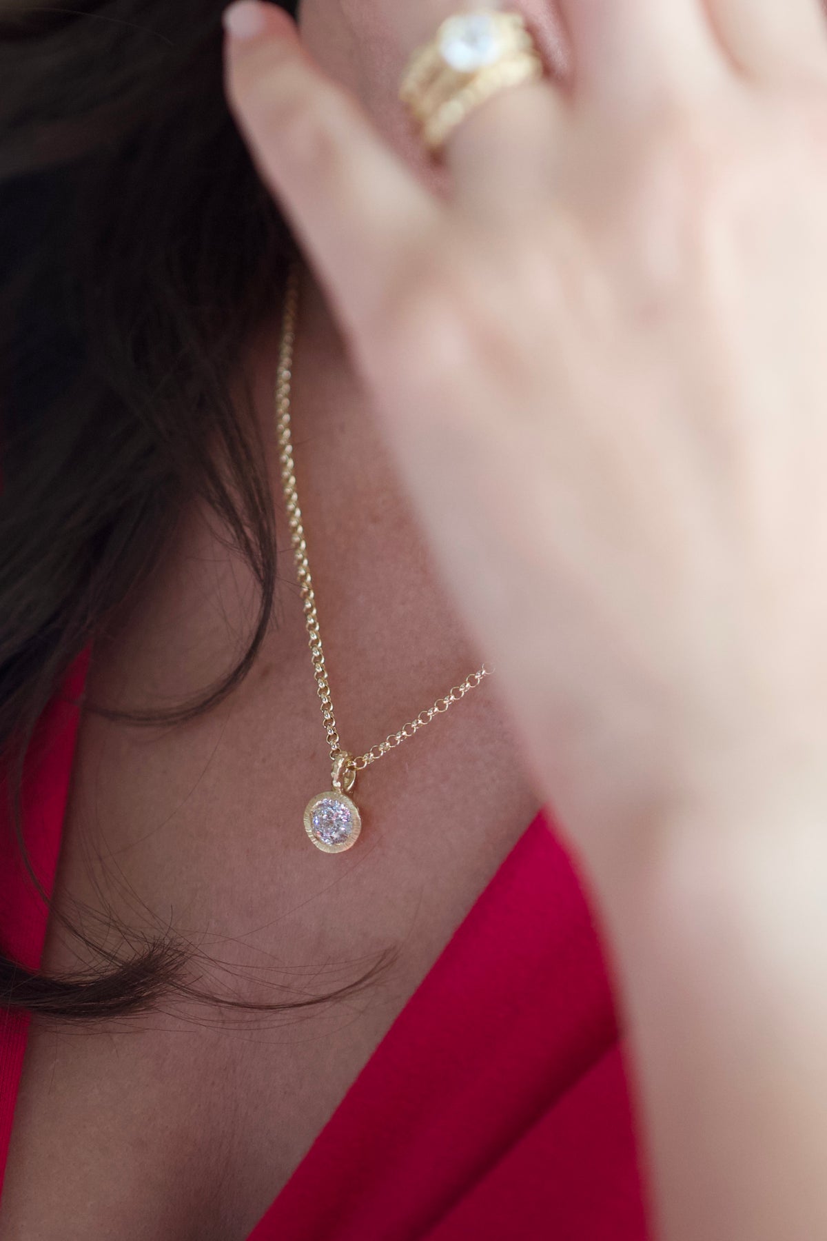 Glypto Diamond Pendant on a fine gold chain, worn at the neckline with a hand near the chain