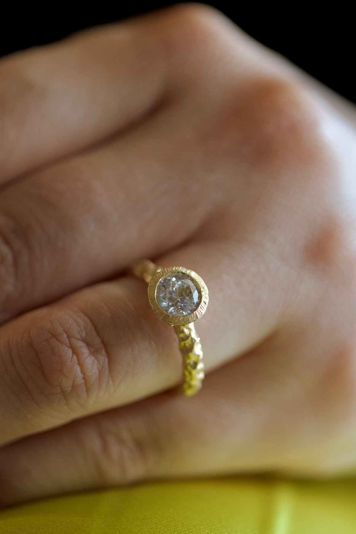 Glypto Solitaire Ring worn on a finger, close view of the bezel set diamond