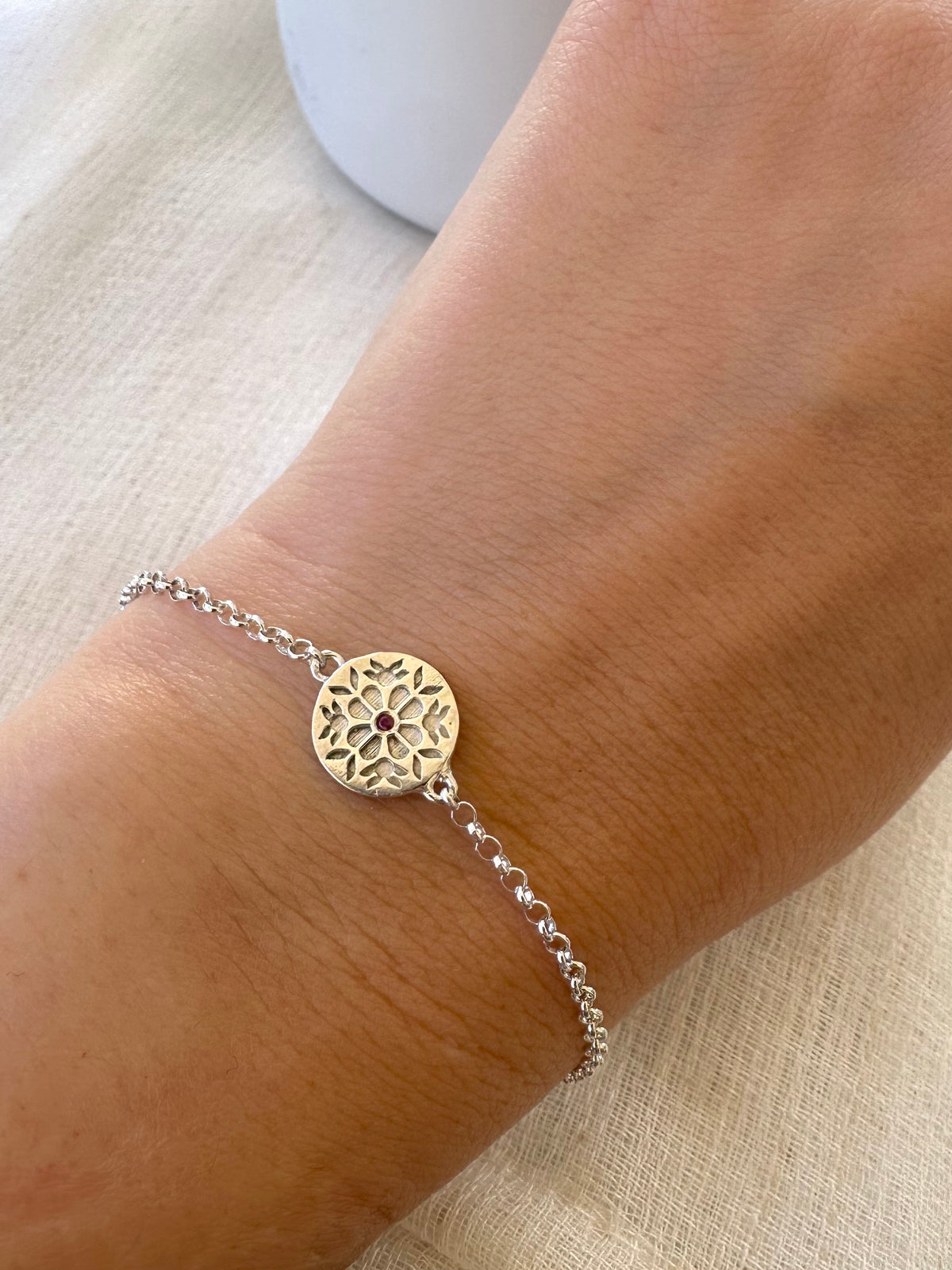 Rolo chain bracelet with a ring clasp and a floral engraved center