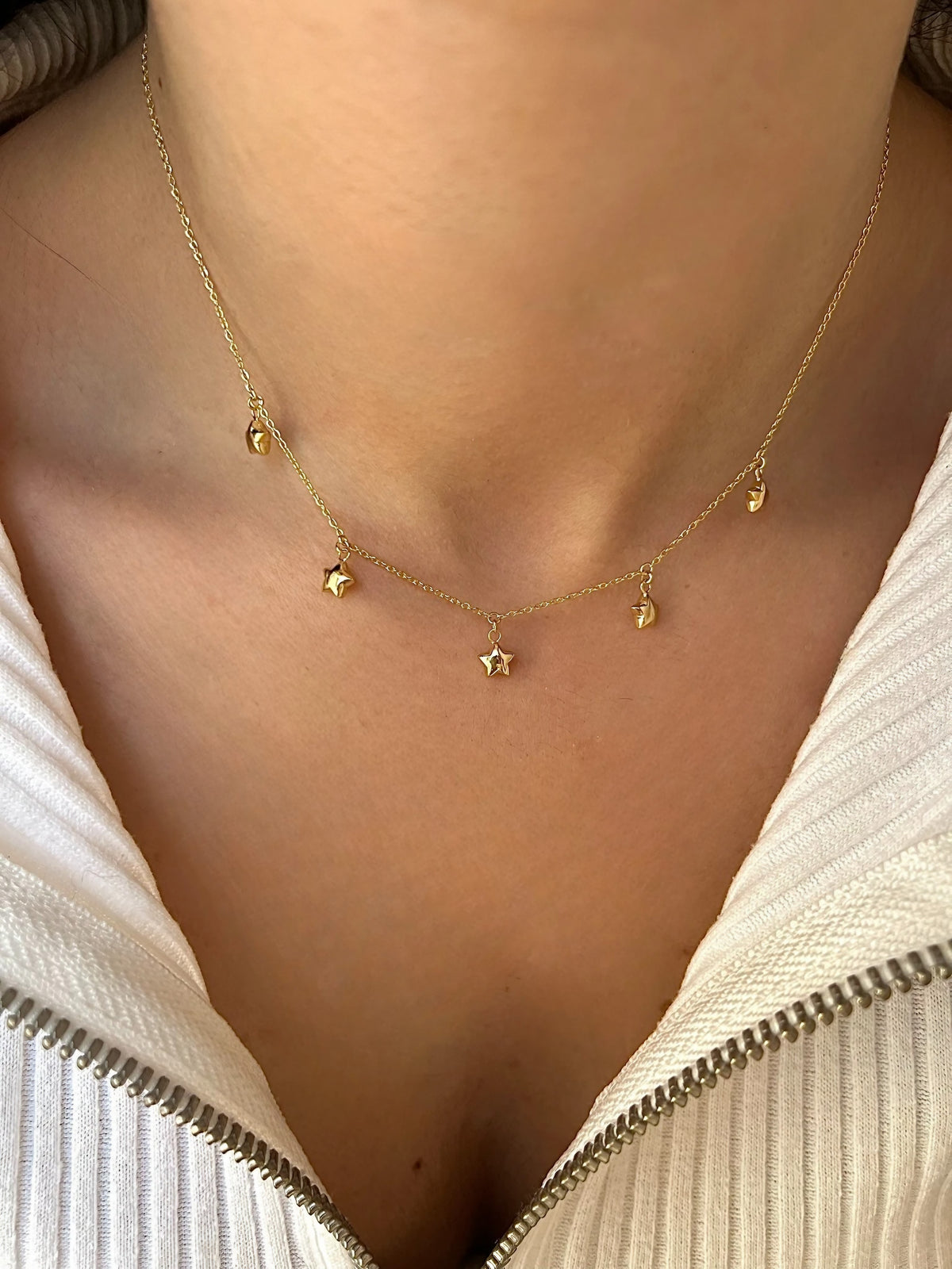 Five domed 18K gold star charms on a dainty chain necklace