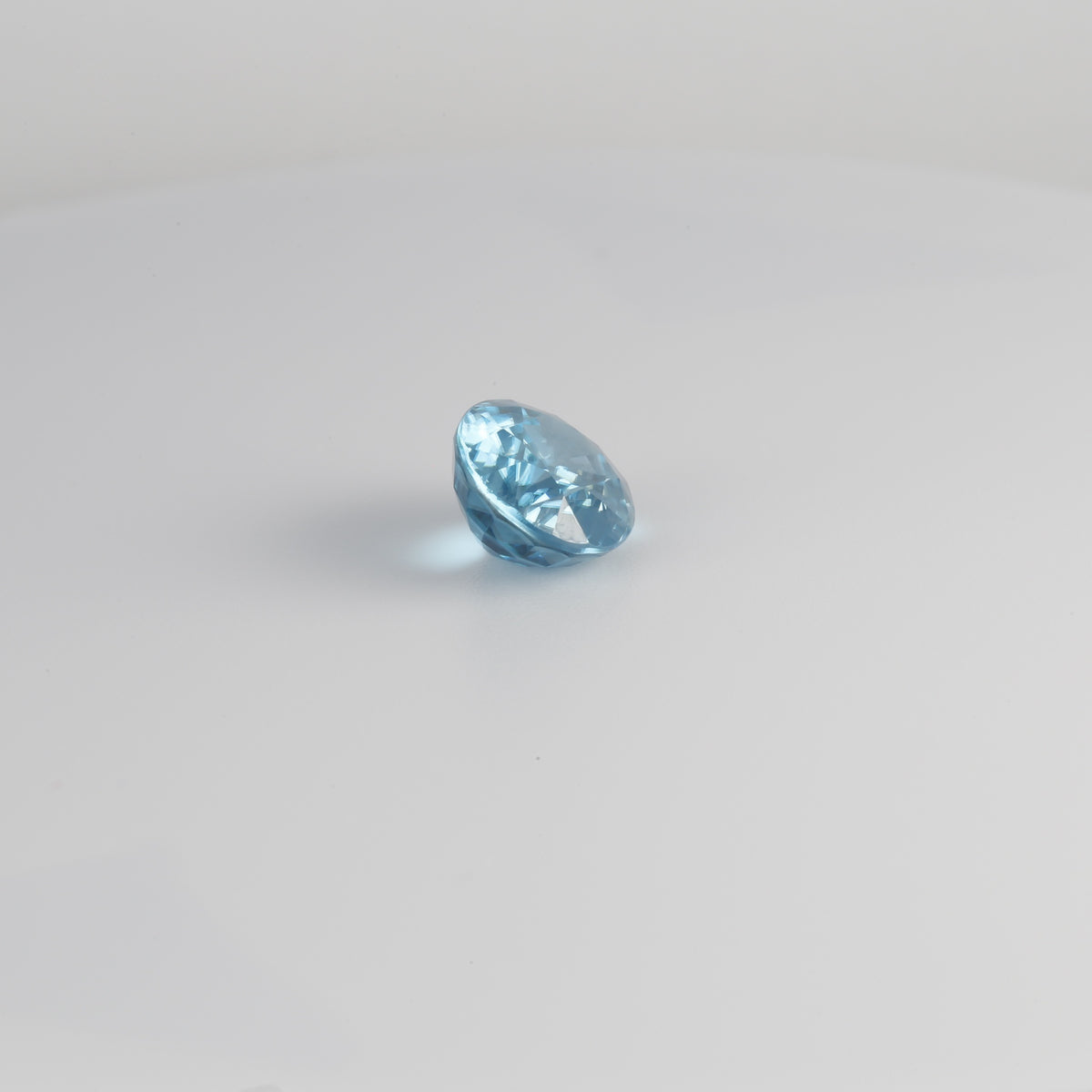 Blue zircon gemstone, 10.8 x 8.4mm, shown at an angle