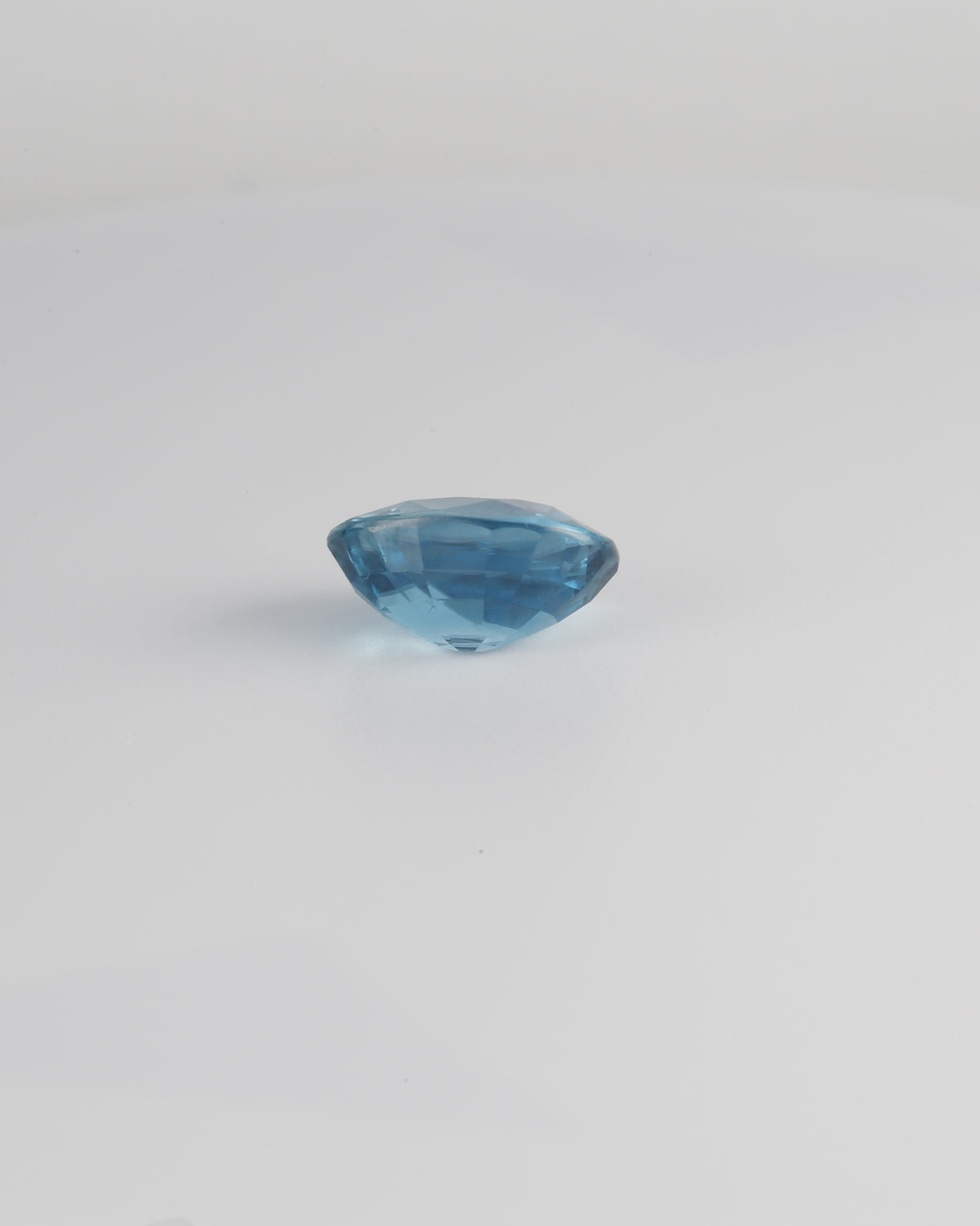 Blue zircon gemstone with a 10.8 x 8.4mm size, in a portrait angle
