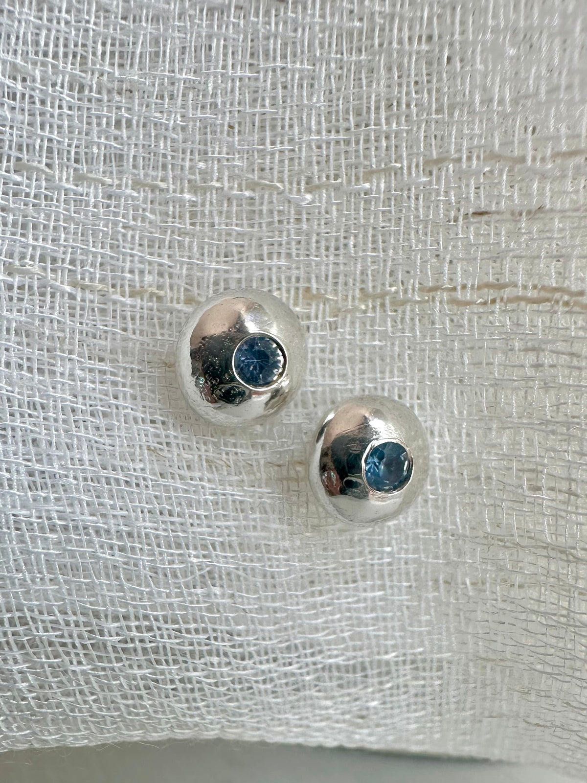 Button stud earring in recycled sterling silver with a flush set blue sapphire at the center | Yasmin Nabulsi Fine Jewelry