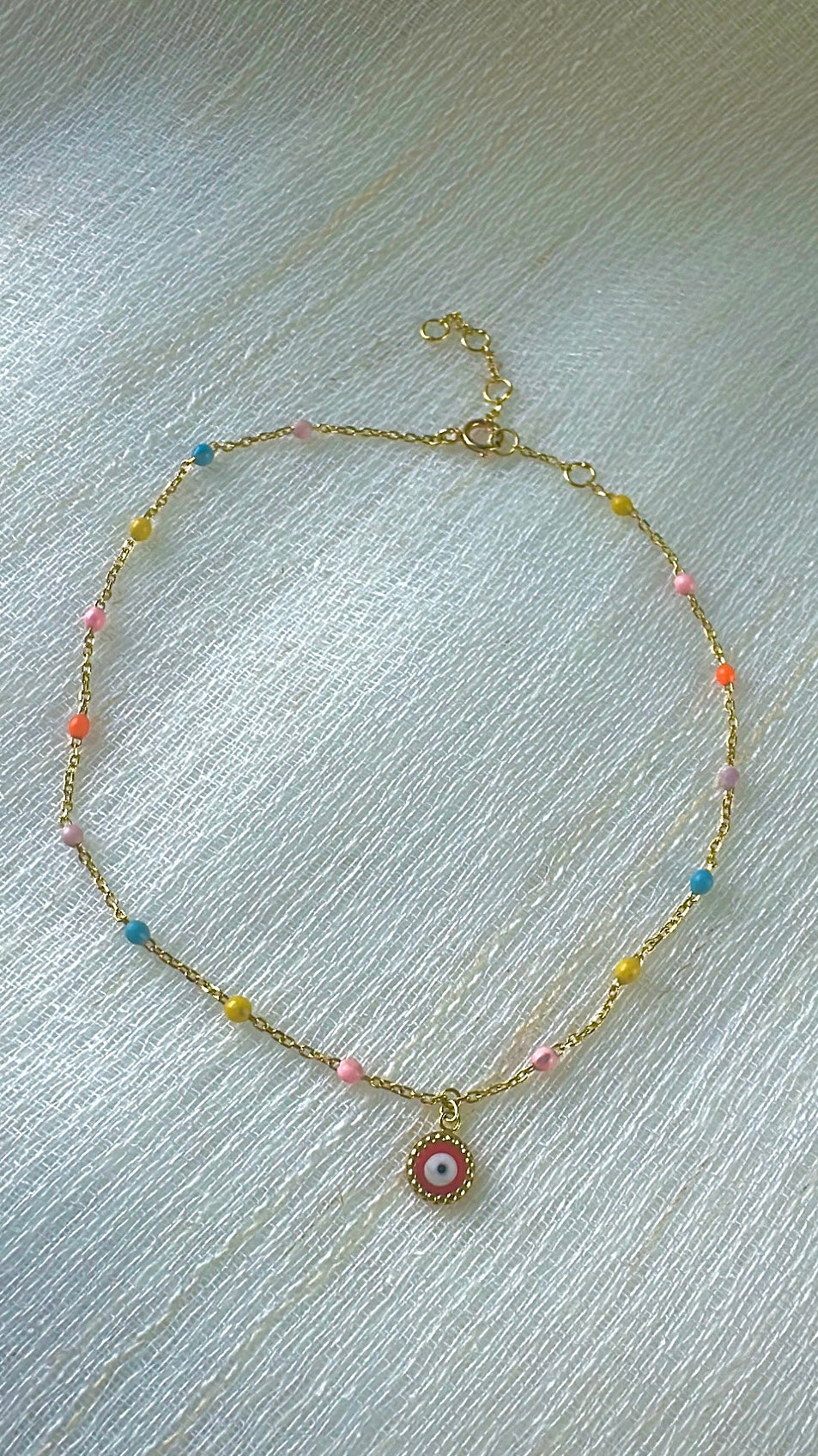 Adjustable 18K gold anklet with colorful enamel points and a dangling evil eye charm