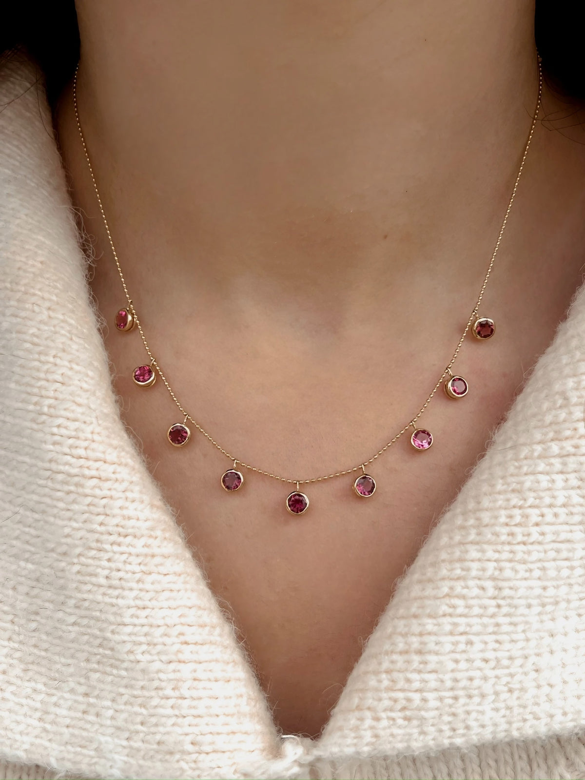 Bezel set pink tourmaline drops on a solid 18K gold ball chain, close-up