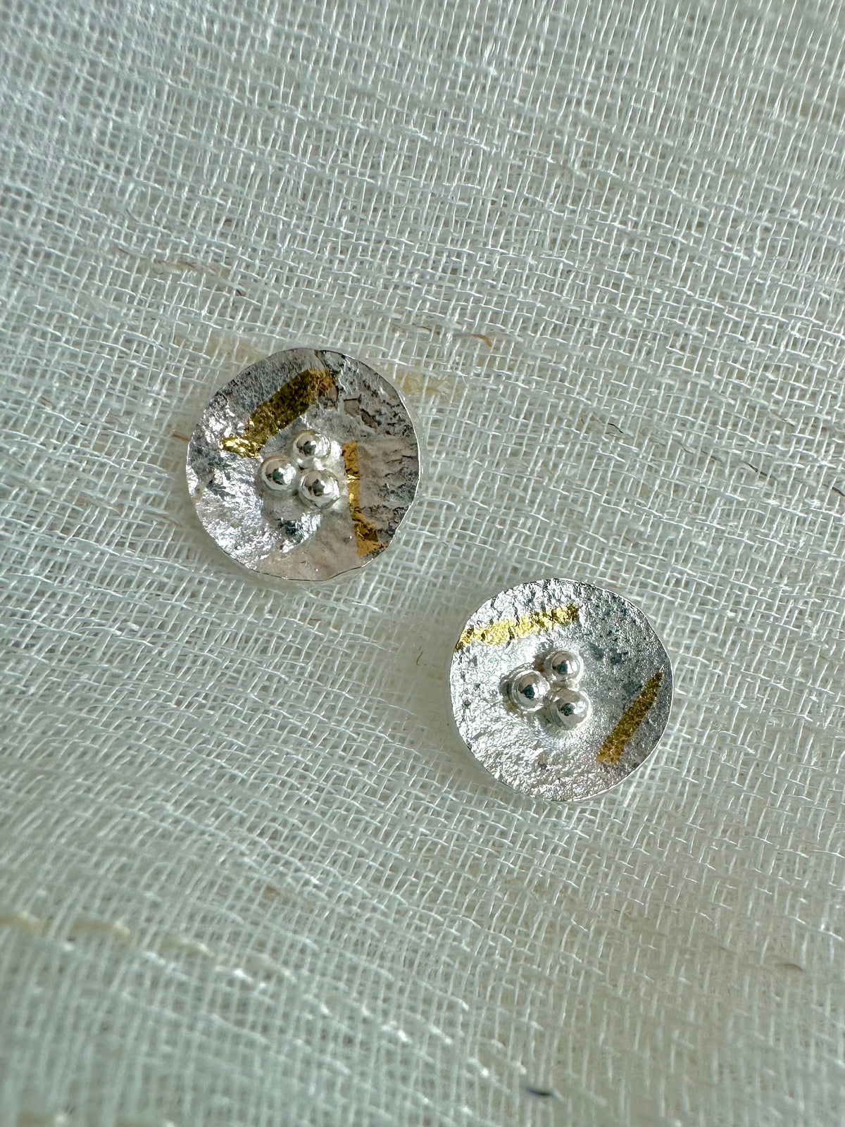 Round silver earrings, slightly concave, with gold foil elements