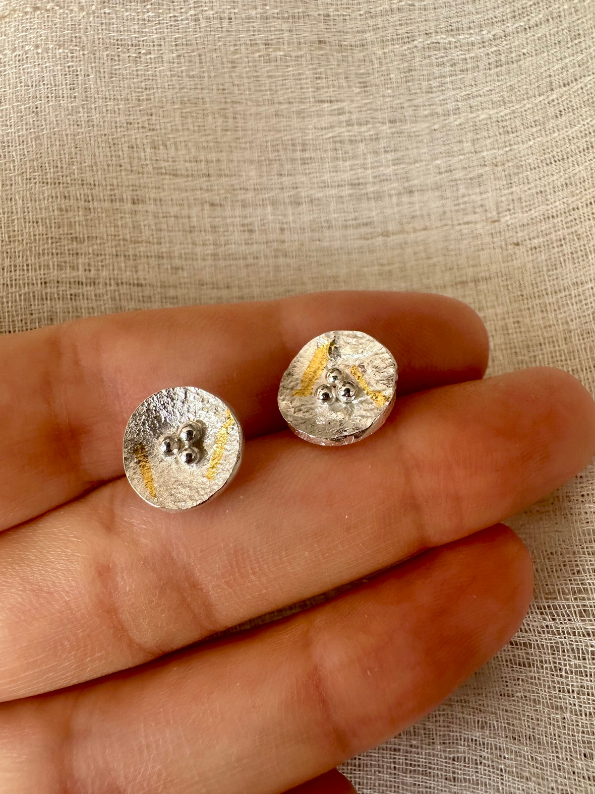Round silver earring with gold foil and a reticulated surface