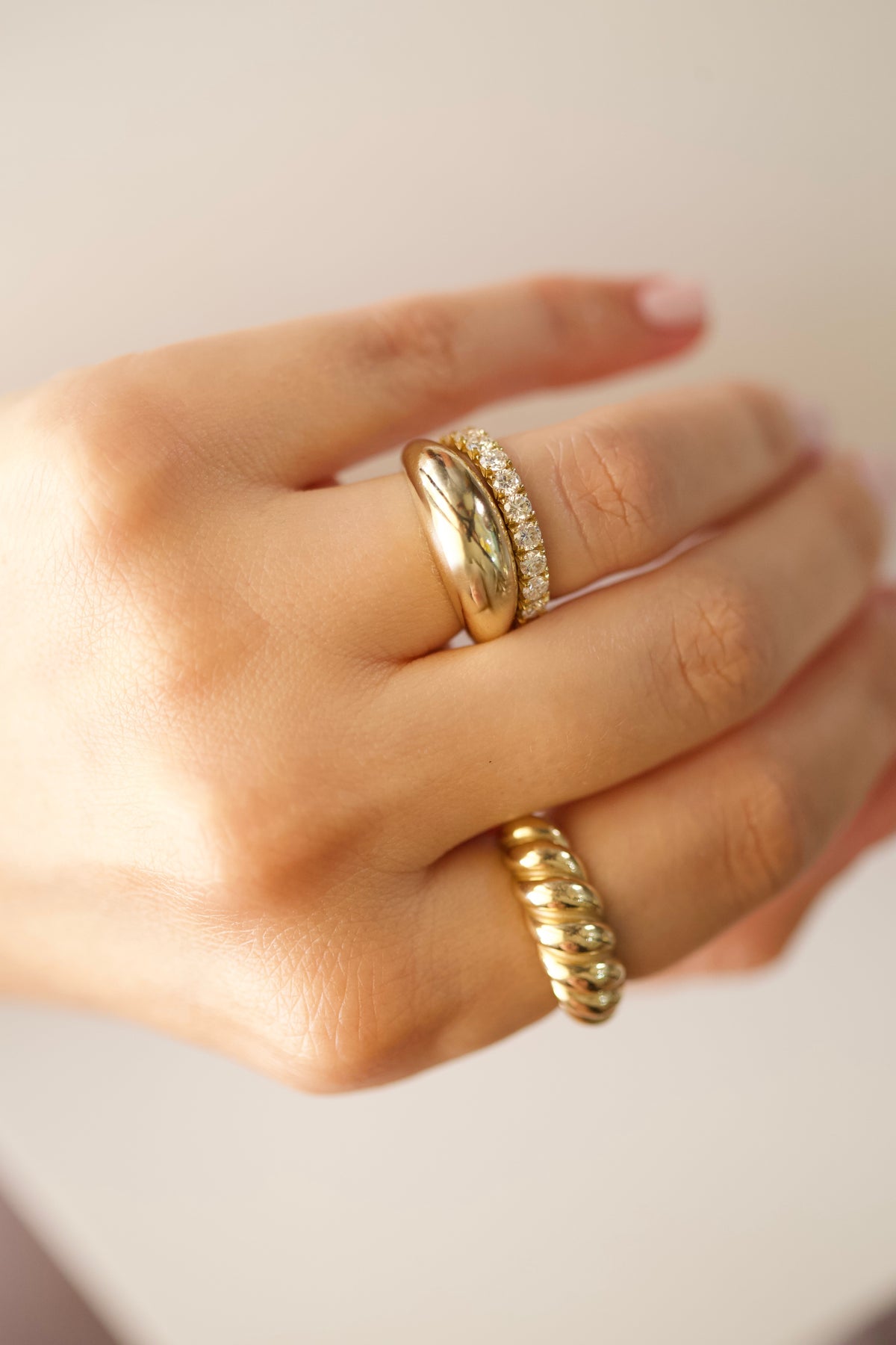 Gold ring stack with a croissant ring, a dome ring and a diamond eternity band