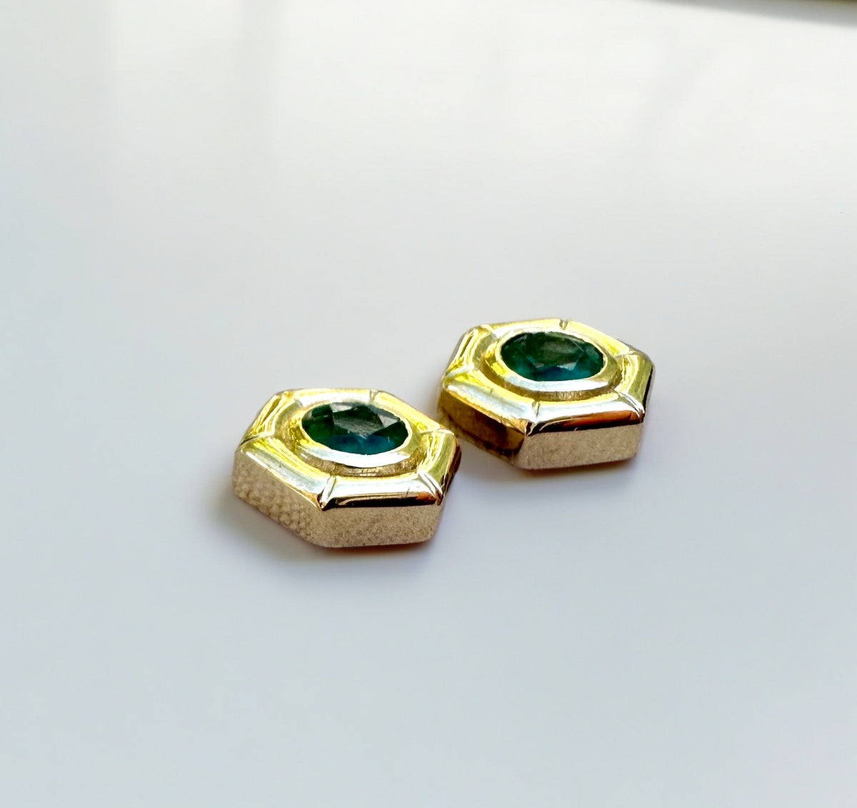 Bezel-set natural emerald, 4mm, in an 18K gold hexagon stud