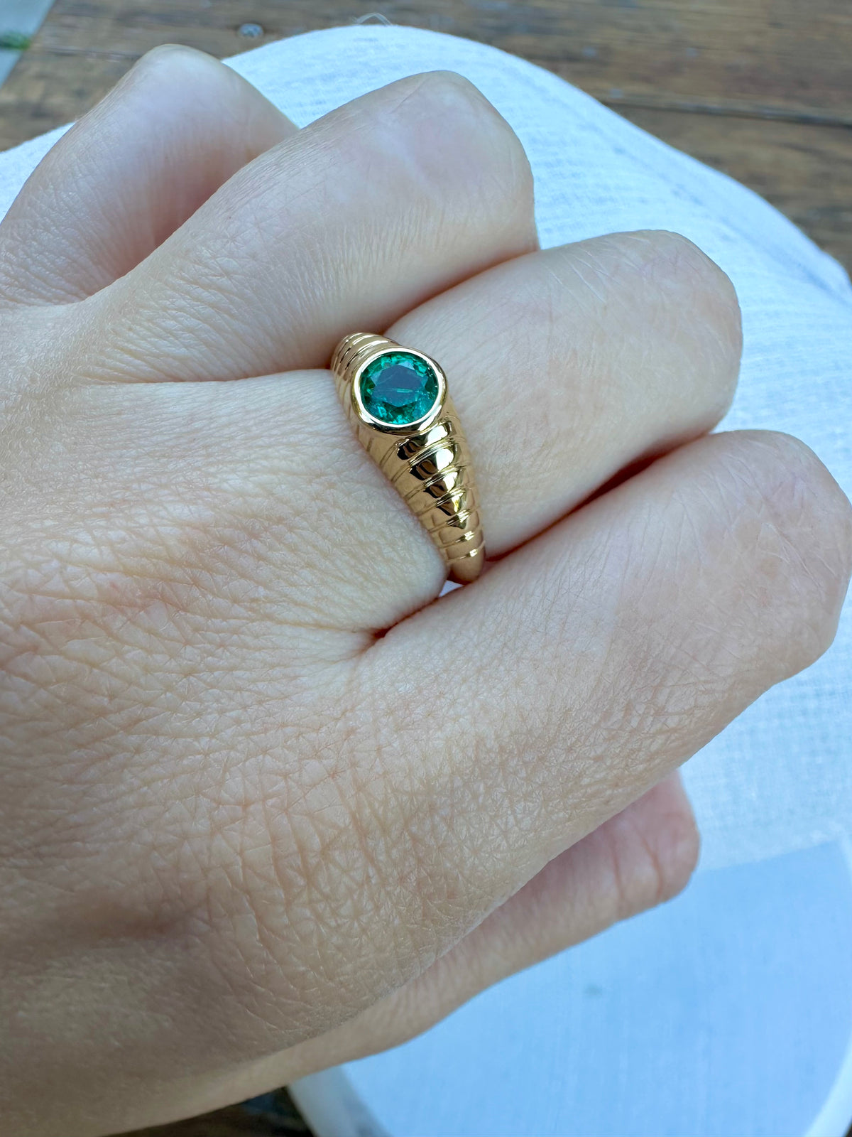 Mina emerald ring close up of the 5mm bezel set stone and ribbed gold band