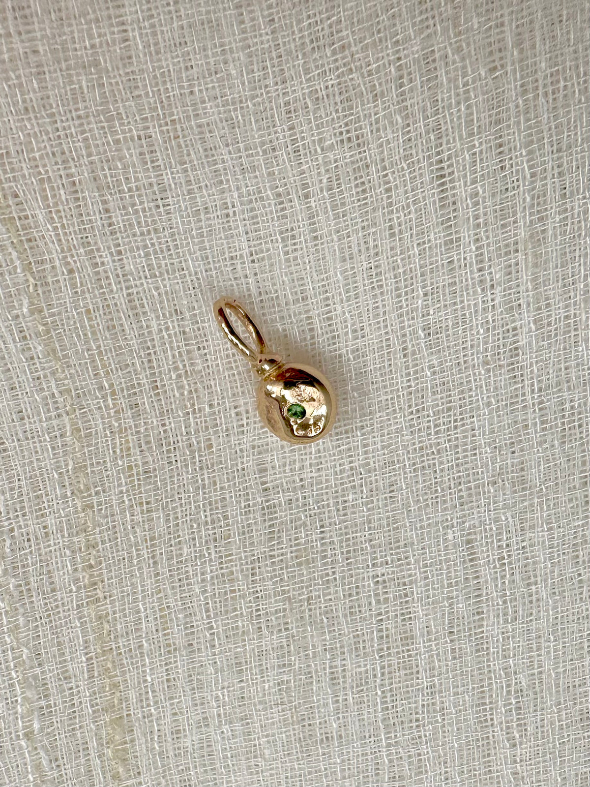 Tsavorite accent on the back of the 14K gold charm, third view