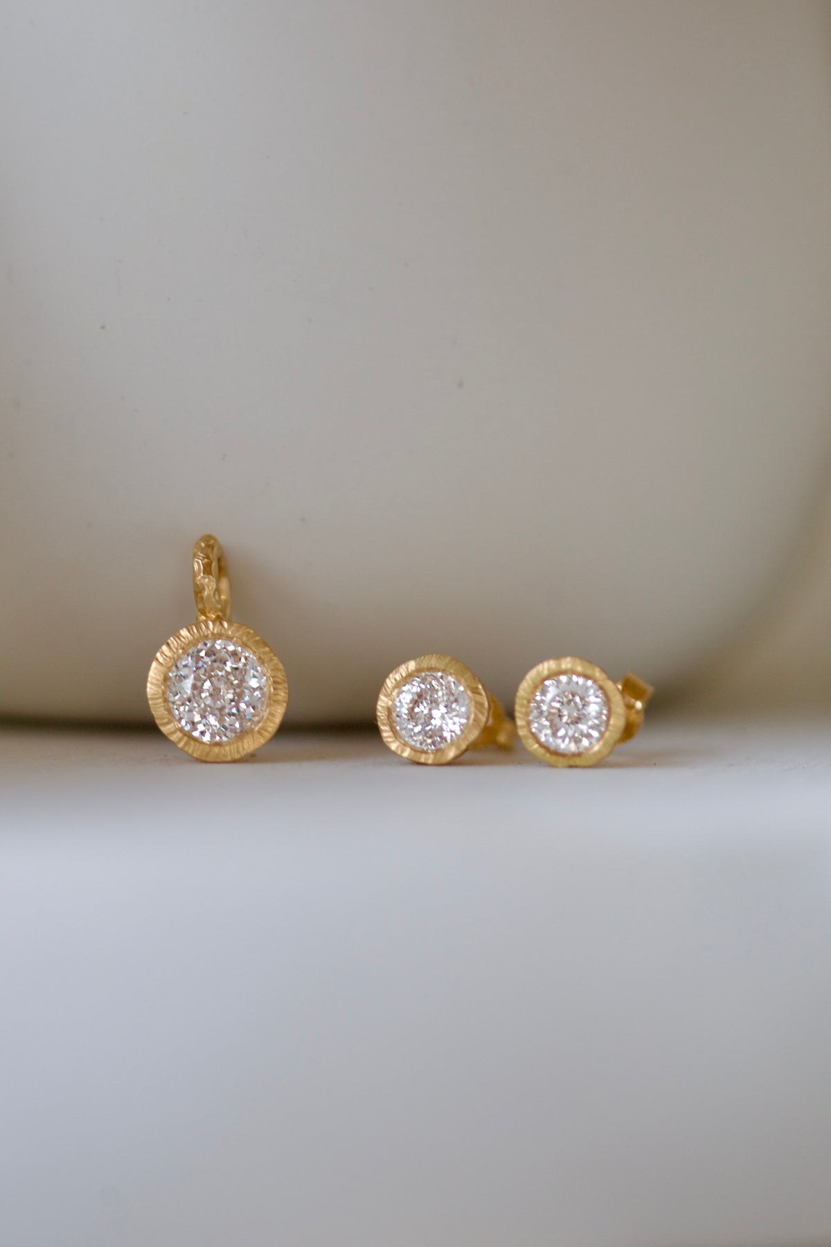 Glypto Diamond Pendant with matching Glypto Diamond Studs on a cream surface
