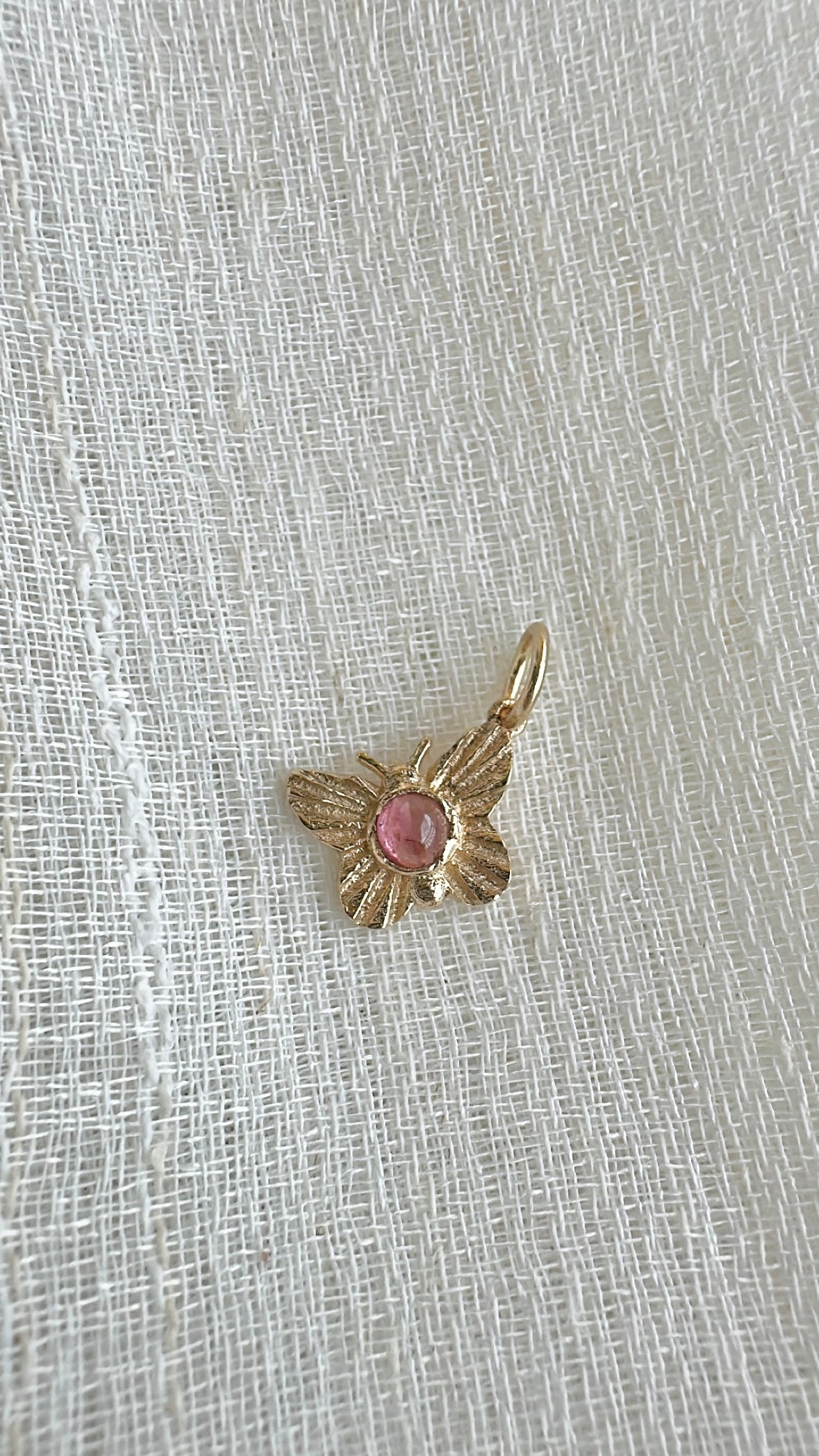 Gold butterfly charm with a round pink tourmaline cabochon in a bezel setting | Yasmin Nabulsi Fine Jewelry