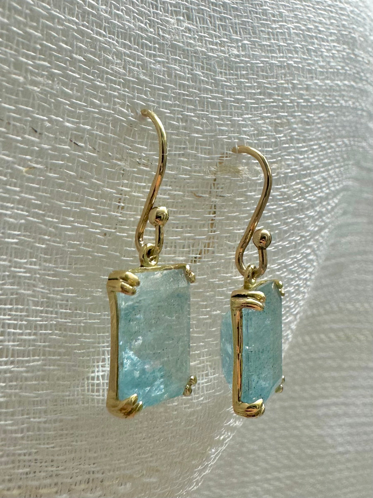 Aquamarine drop earrings with a 13x8mm emerald cut stone in an open back prong setting