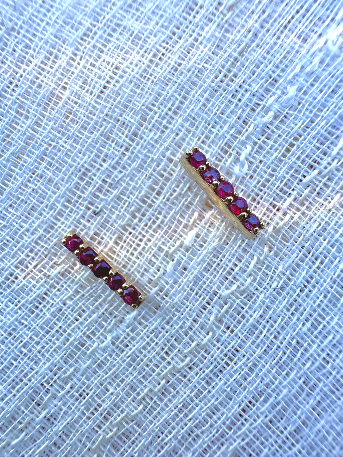 Round 1.7mm natural rubies set in a linear 18 karat gold bar stud