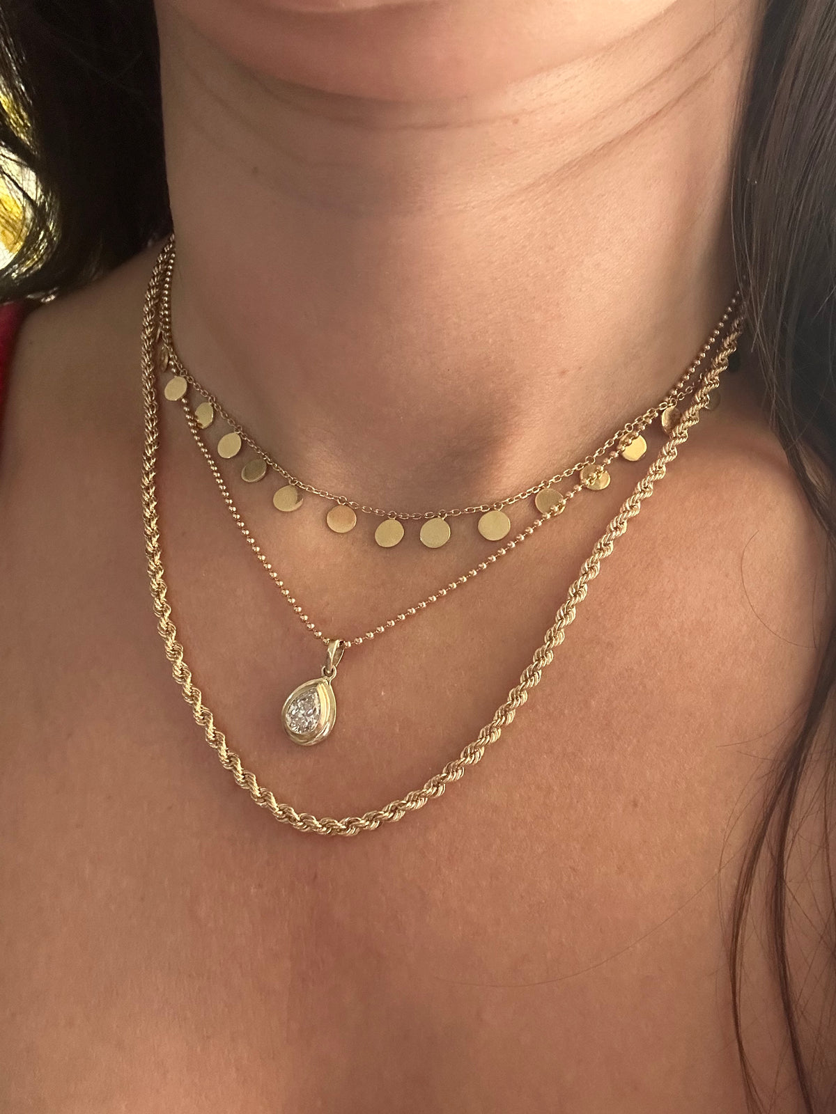 Layered 18K gold necklaces with a disc necklace and a diamond pendant