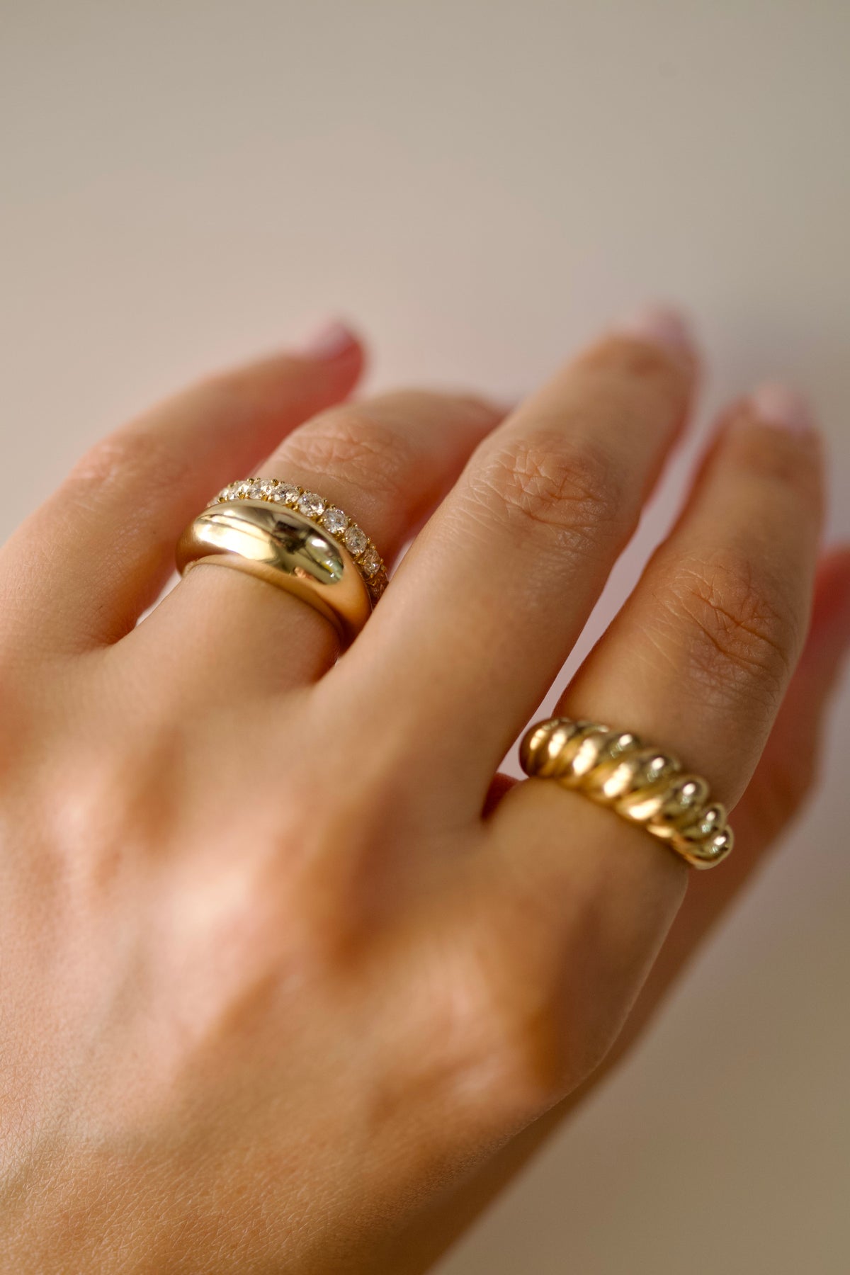Twisted croissant ring and gold dome ring worn in a ring stack