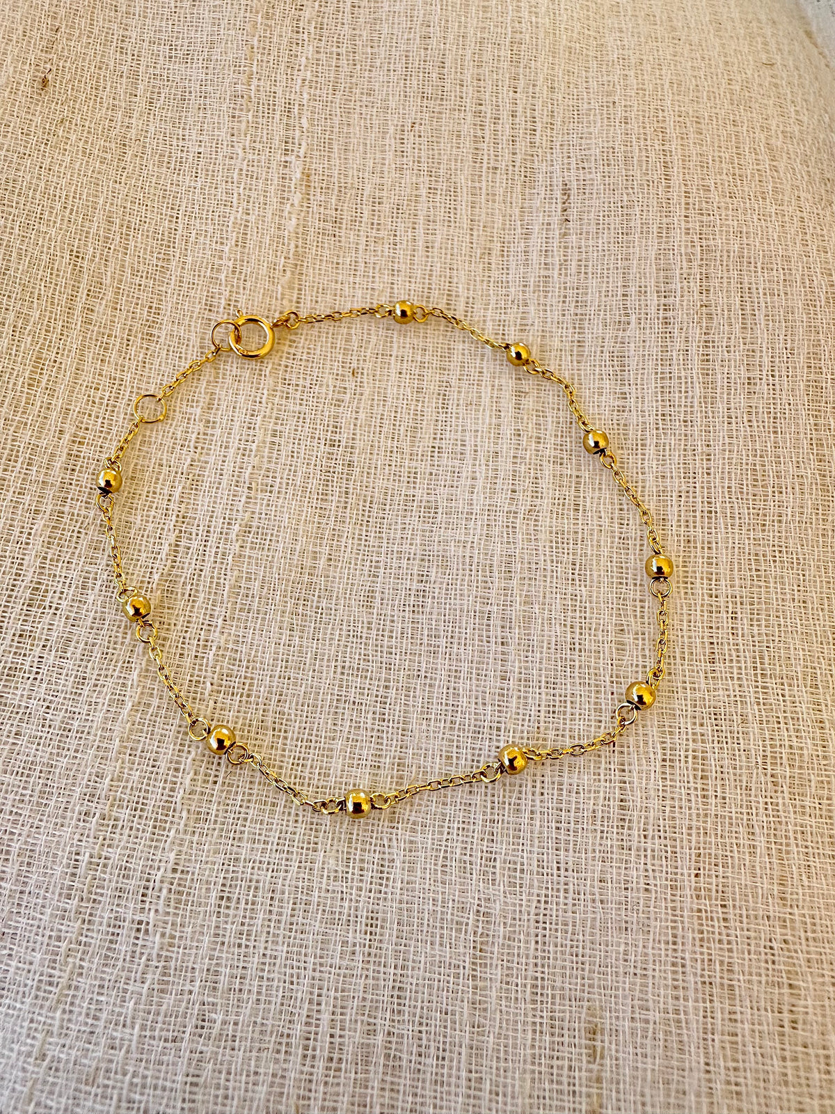 Thin gold ball bracelet on a delicate chain, made for wearing alone or stacking