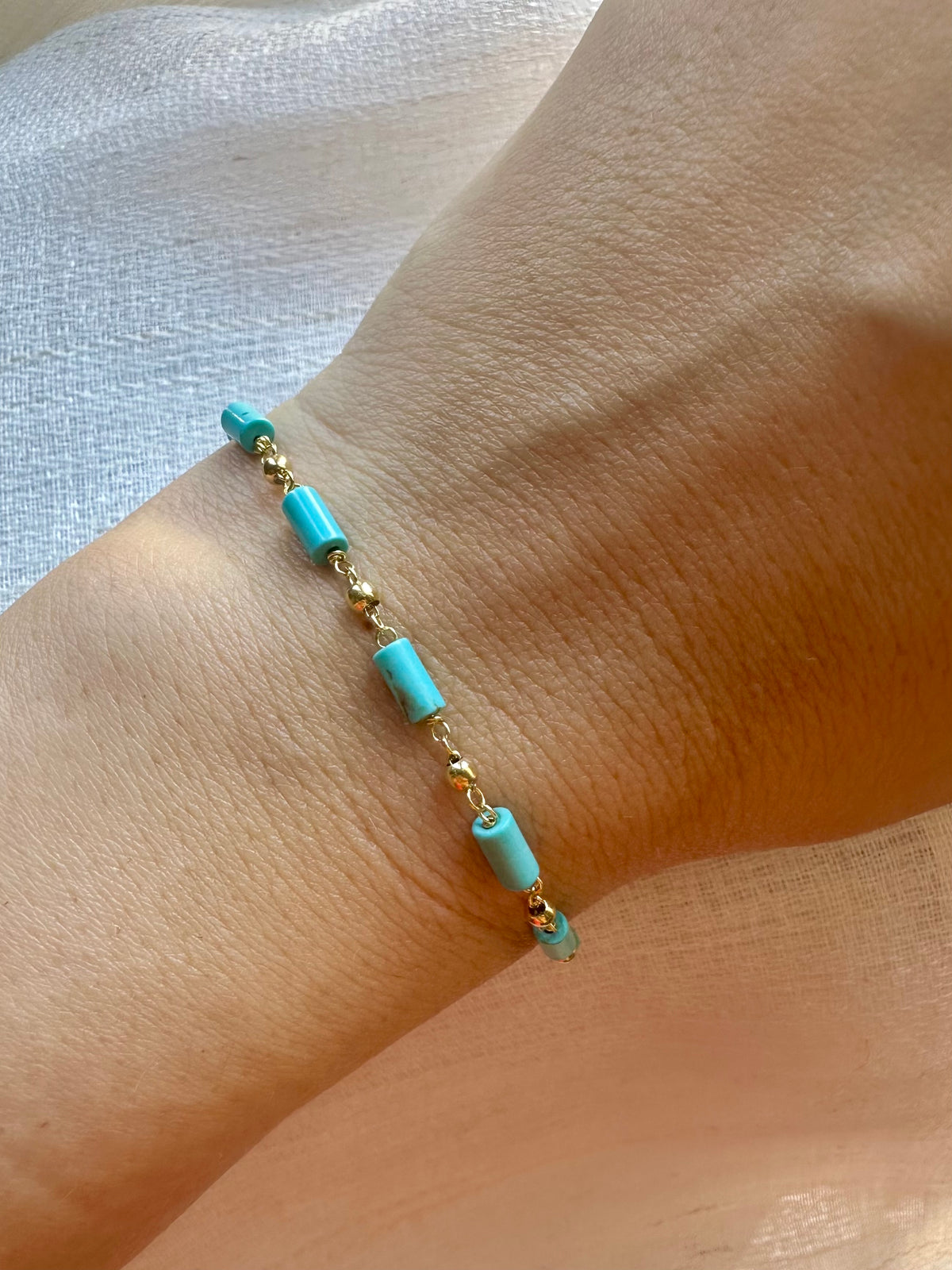 Turquoise tube beads and gold beads on a handcrafted 18K gold wire bracelet