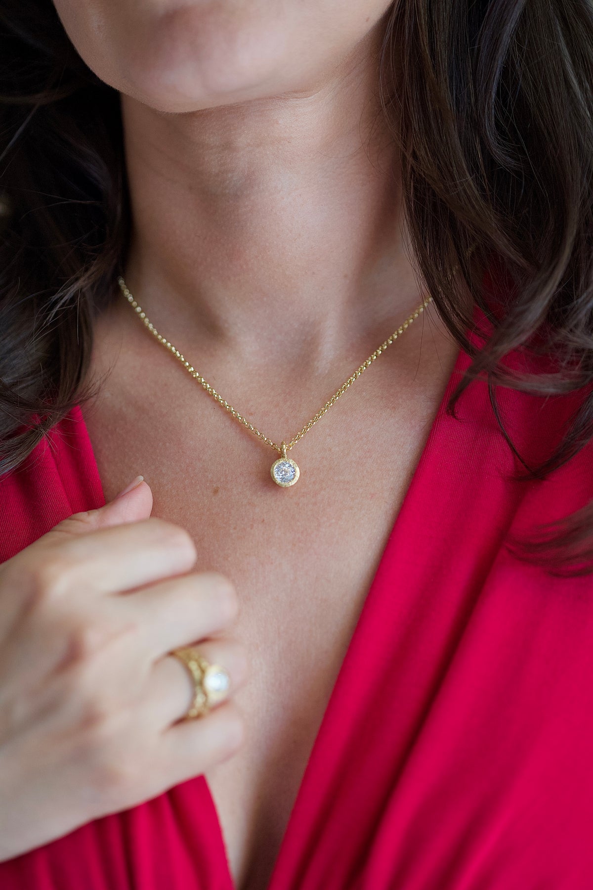 Glypto Diamond Pendant on a fine gold chain, worn, with a hand resting at the neckline