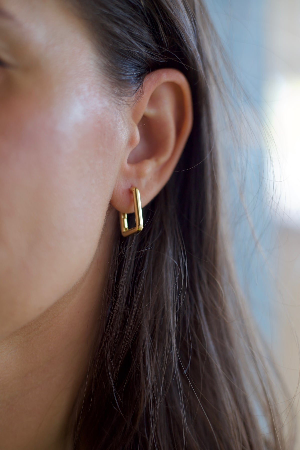 Rectangular gold hoop earrings, 19mm long and 3mm wide, sitting close to the ear