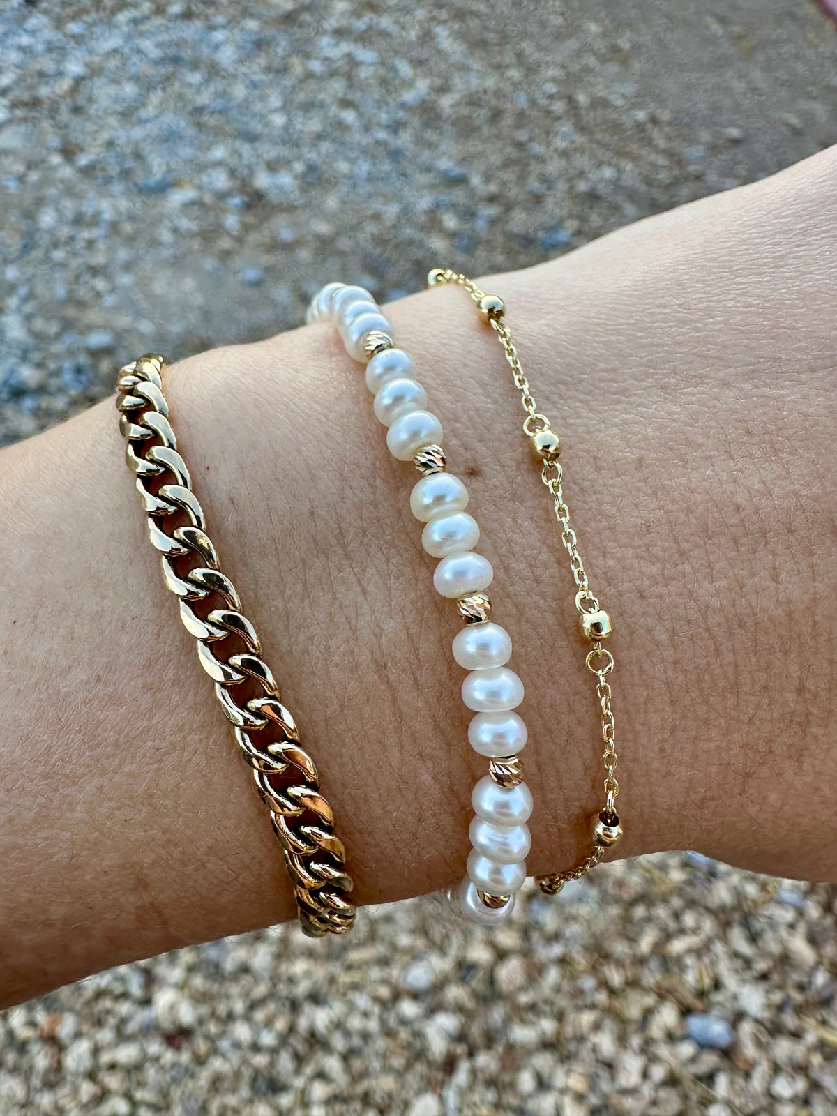 Stack of 18K gold bracelets with a Cuban link and a gold chain bracelet
