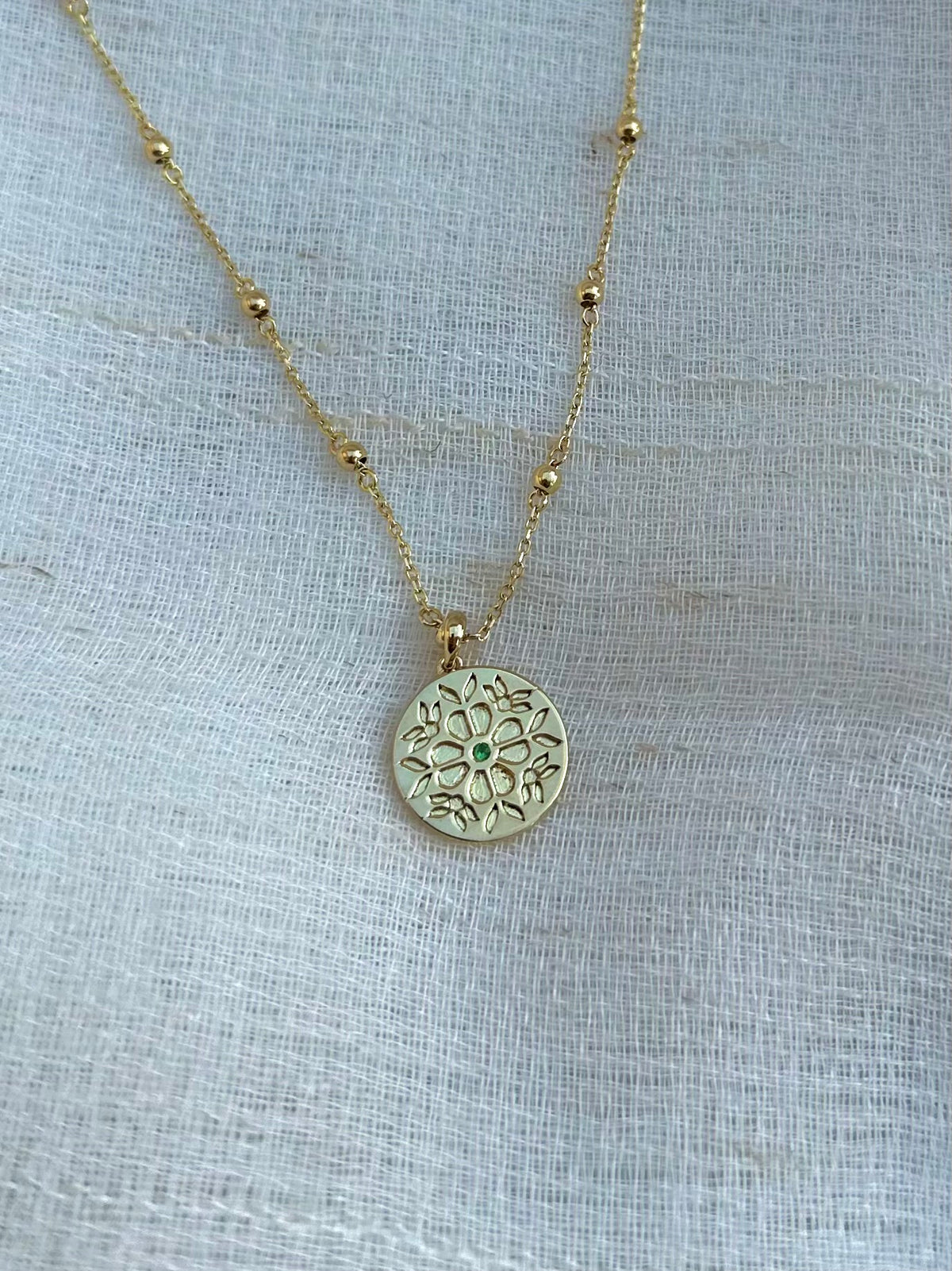 Gold coin pendant with a floral CAD engraved pattern and a customizable center stone