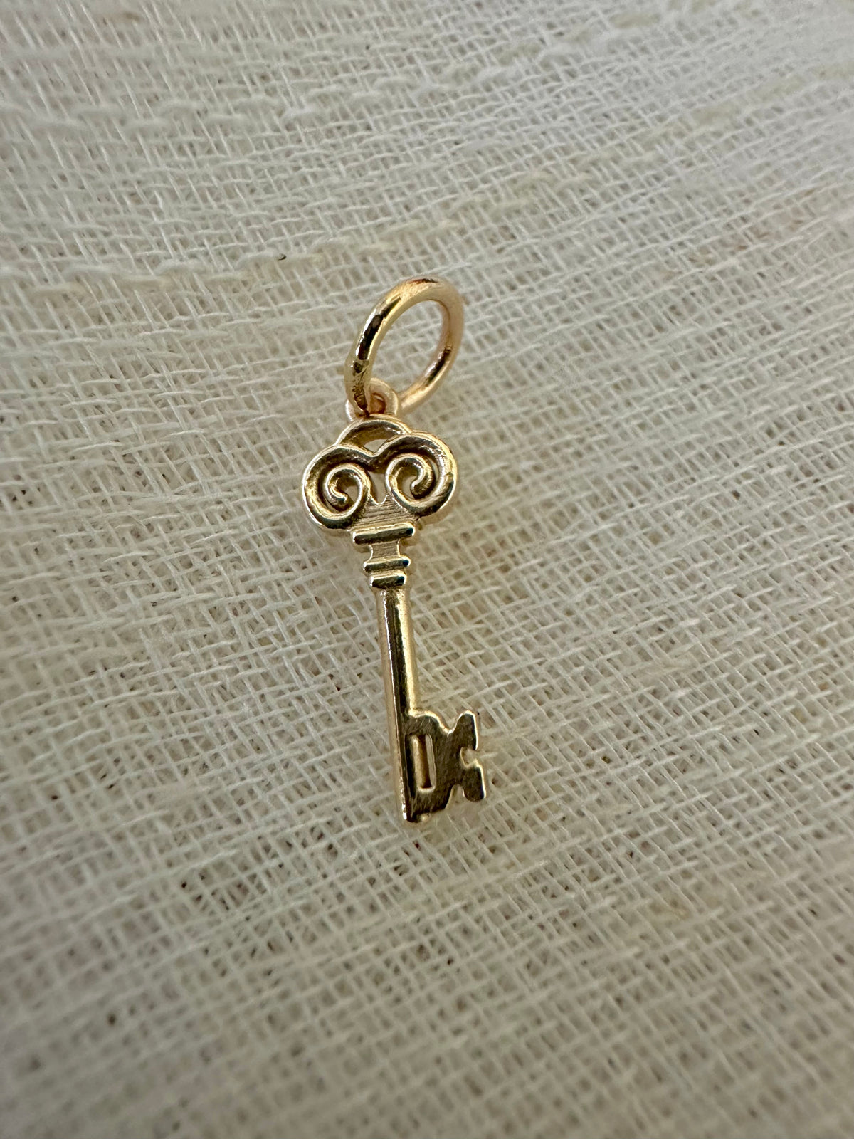 Gold key charm inspired by the Key of Return, available in 14K and 18K gold