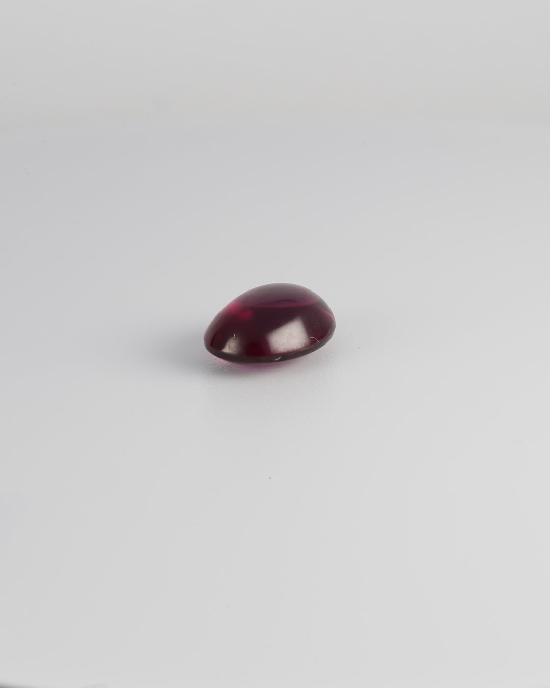 Purple garnet oval cabochon, 10 x 7.4mm, in a portrait angle view