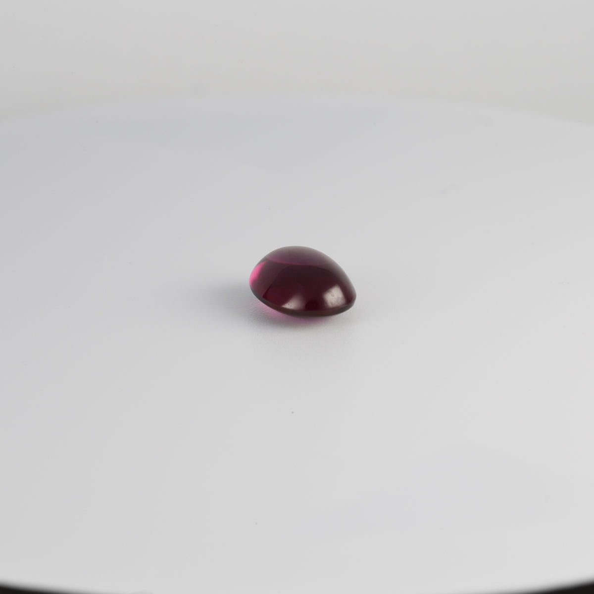 Purple garnet oval cabochon in an angled view
