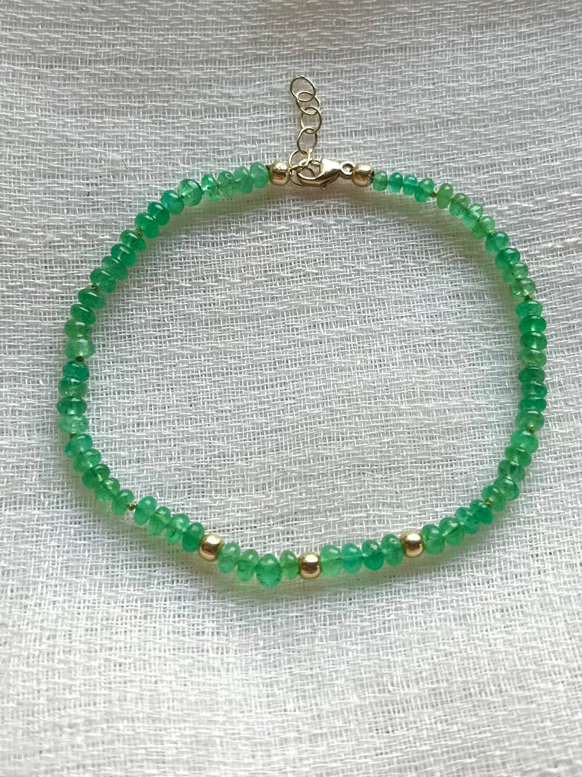 Emerald beads strung on silk thread with gold findings