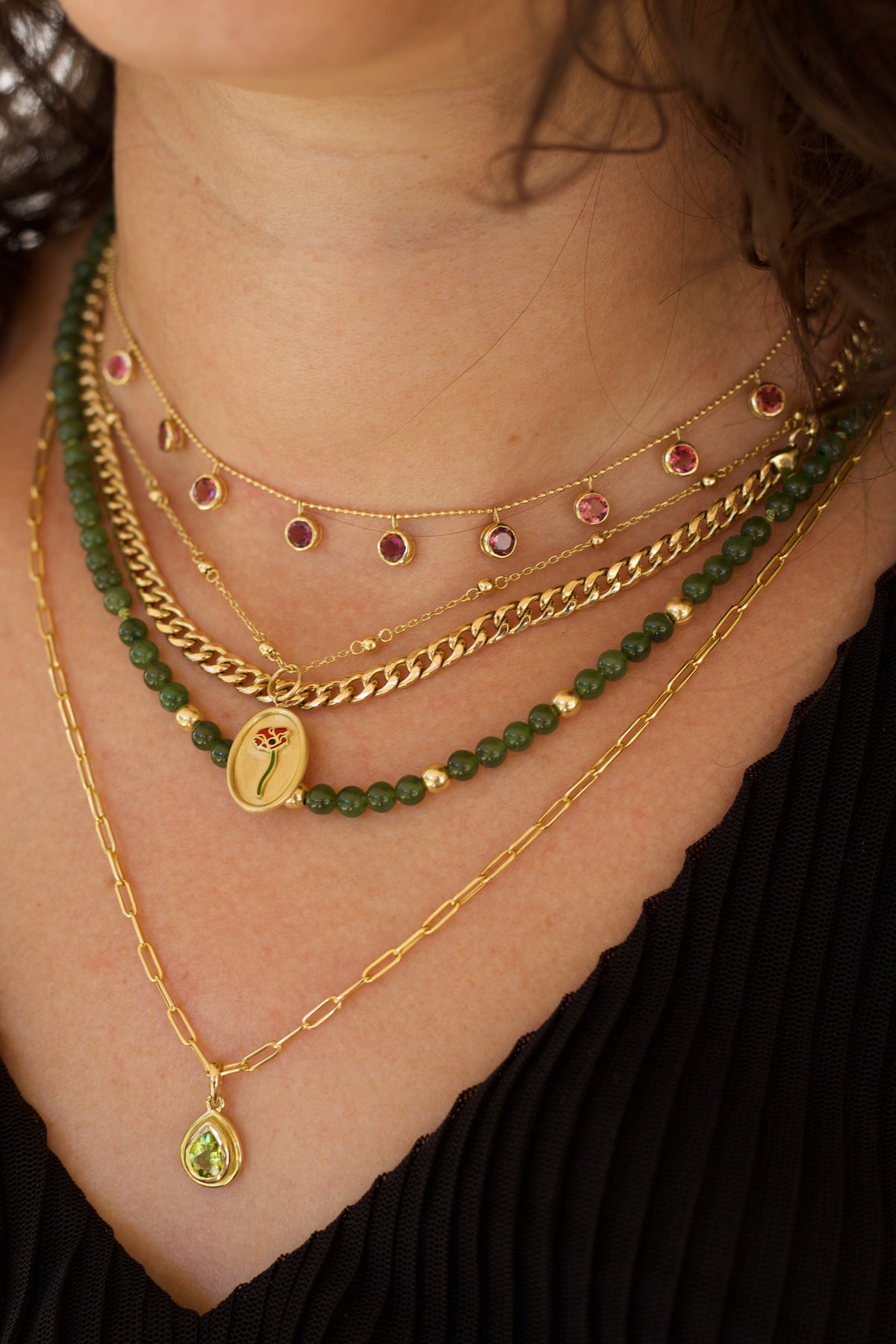 Layered gold necklace stack with a pink tourmaline necklace