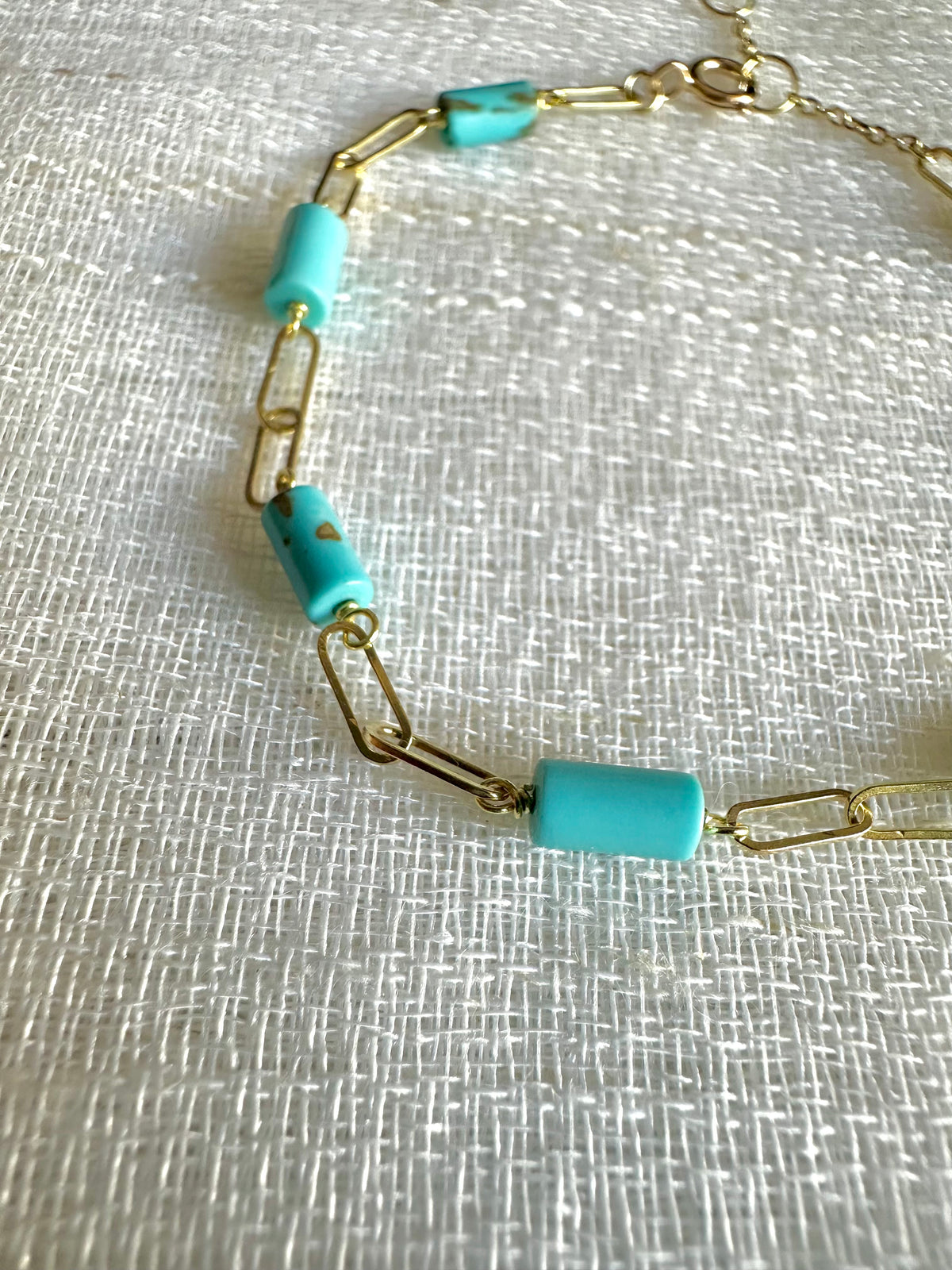 Gold paperclip bracelet with turquoise beads, shown from another angle