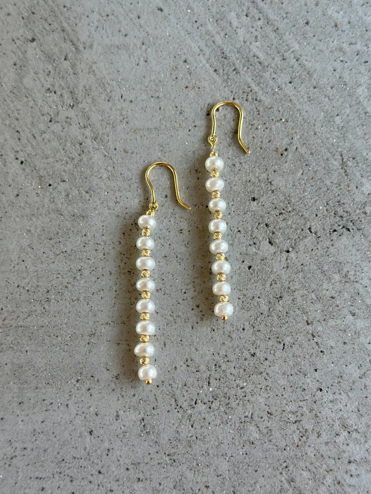 Gold chain running through freshwater pearls and gold beads on each earring