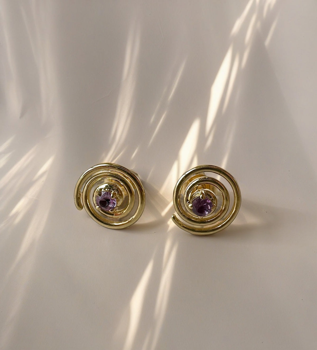 Spiral gold stud with a sapphire center, minimalistic and unique