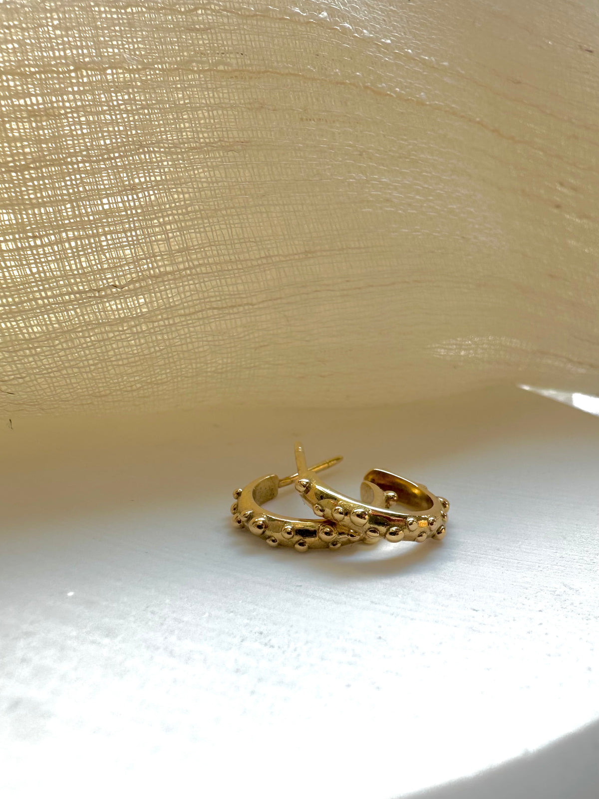 Solid gold hoop earrings with a D-shape wire and granule detail along the outer top